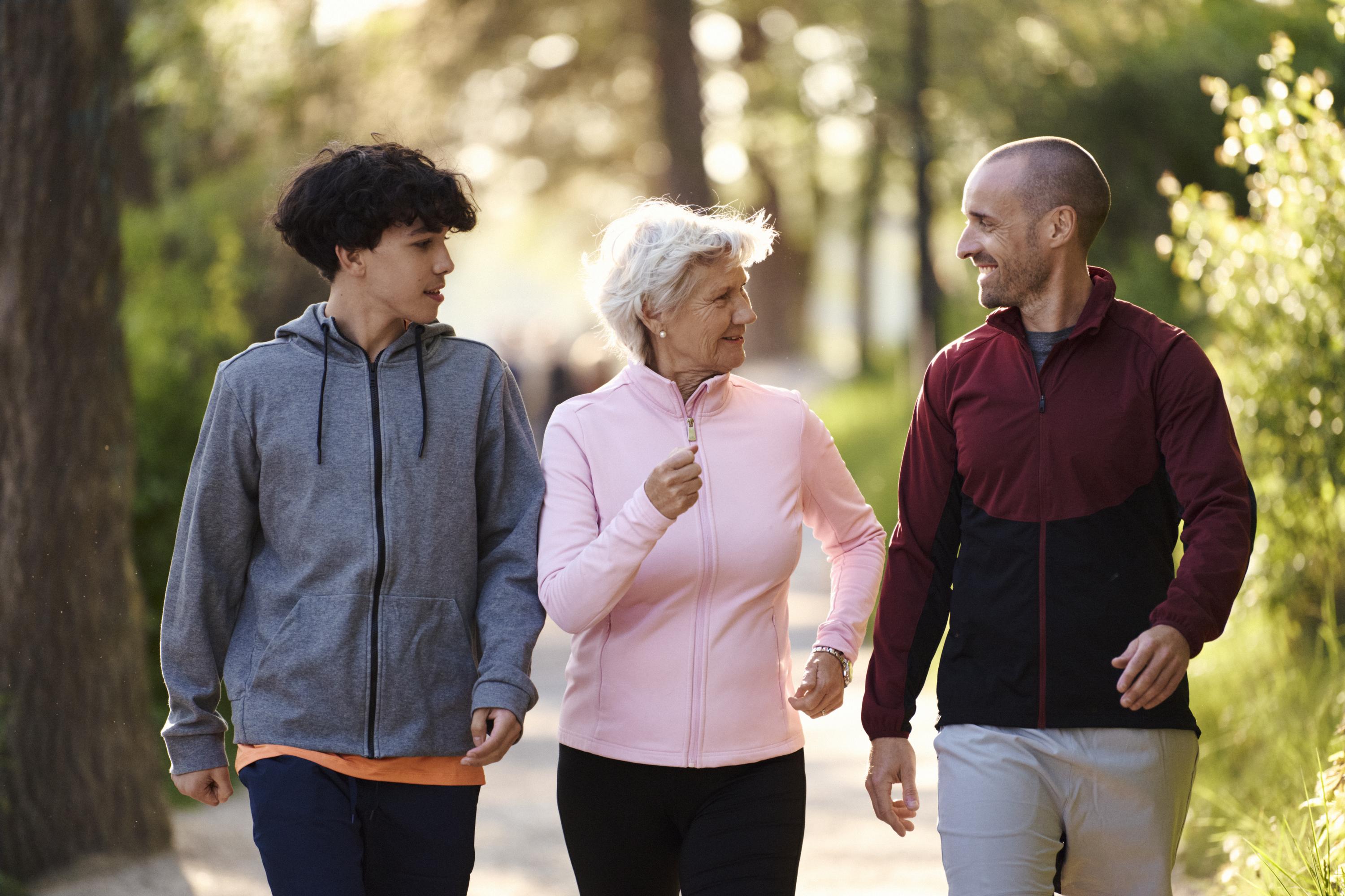 Tre personer i olika åldrar är ute på promenad tillsammans