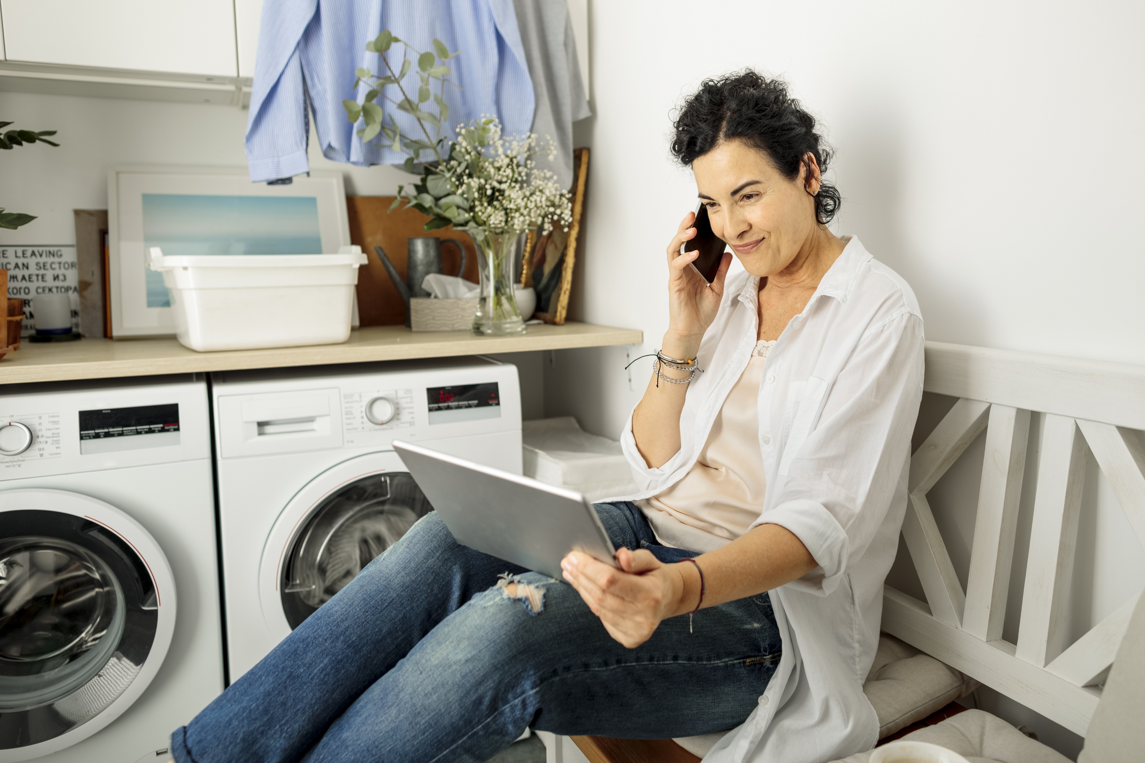 Kvinna i pratar i telefon i tvättstugan